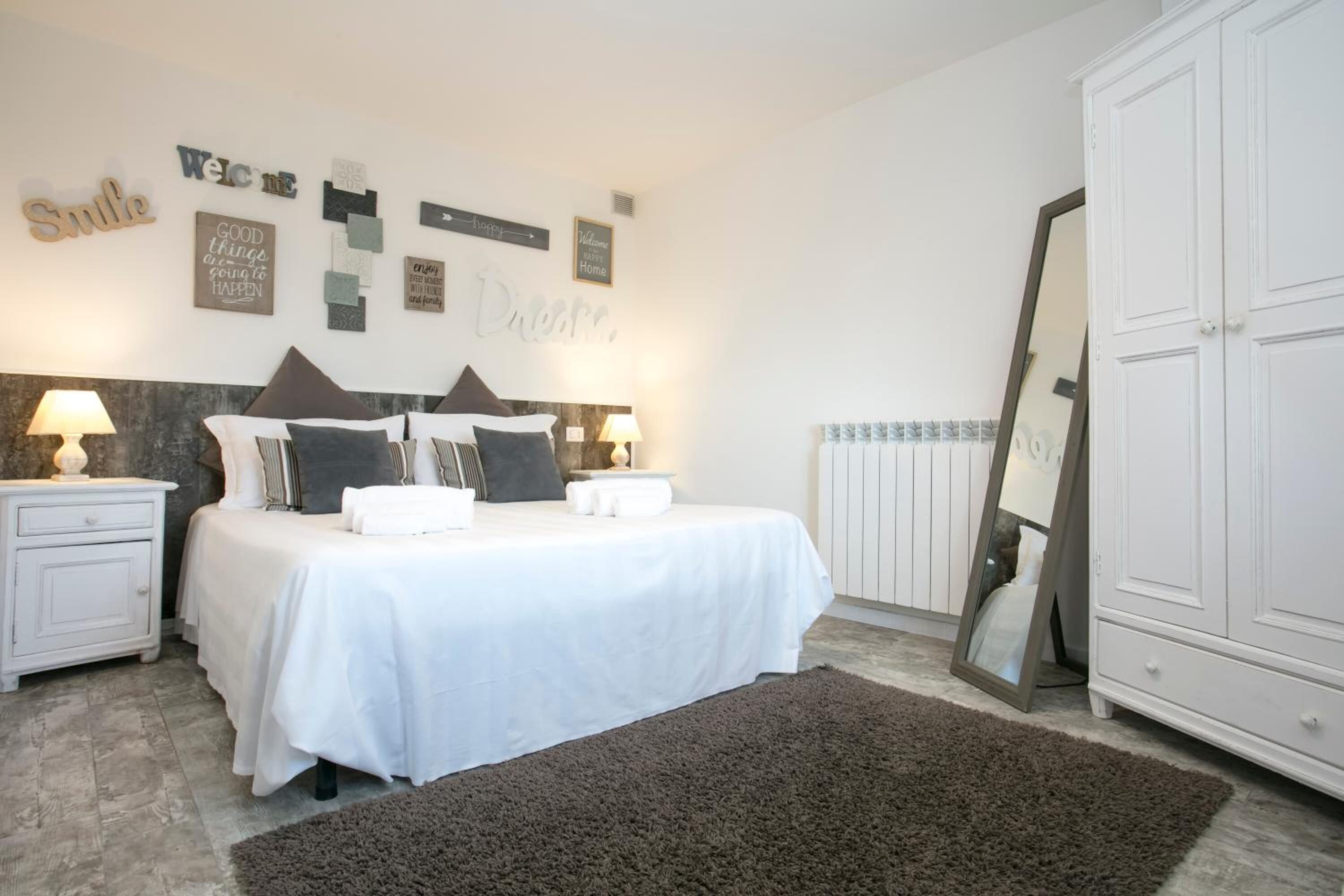 A bedroom with a bed, bedside tables, a mirror, and wall decorations.