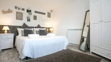 A bedroom with a bed, bedside tables, a mirror, and wall decorations.