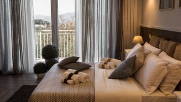 A bedroom with a bed, pillows, a nightstand, a lamp, and a view of a balcony with a railing.