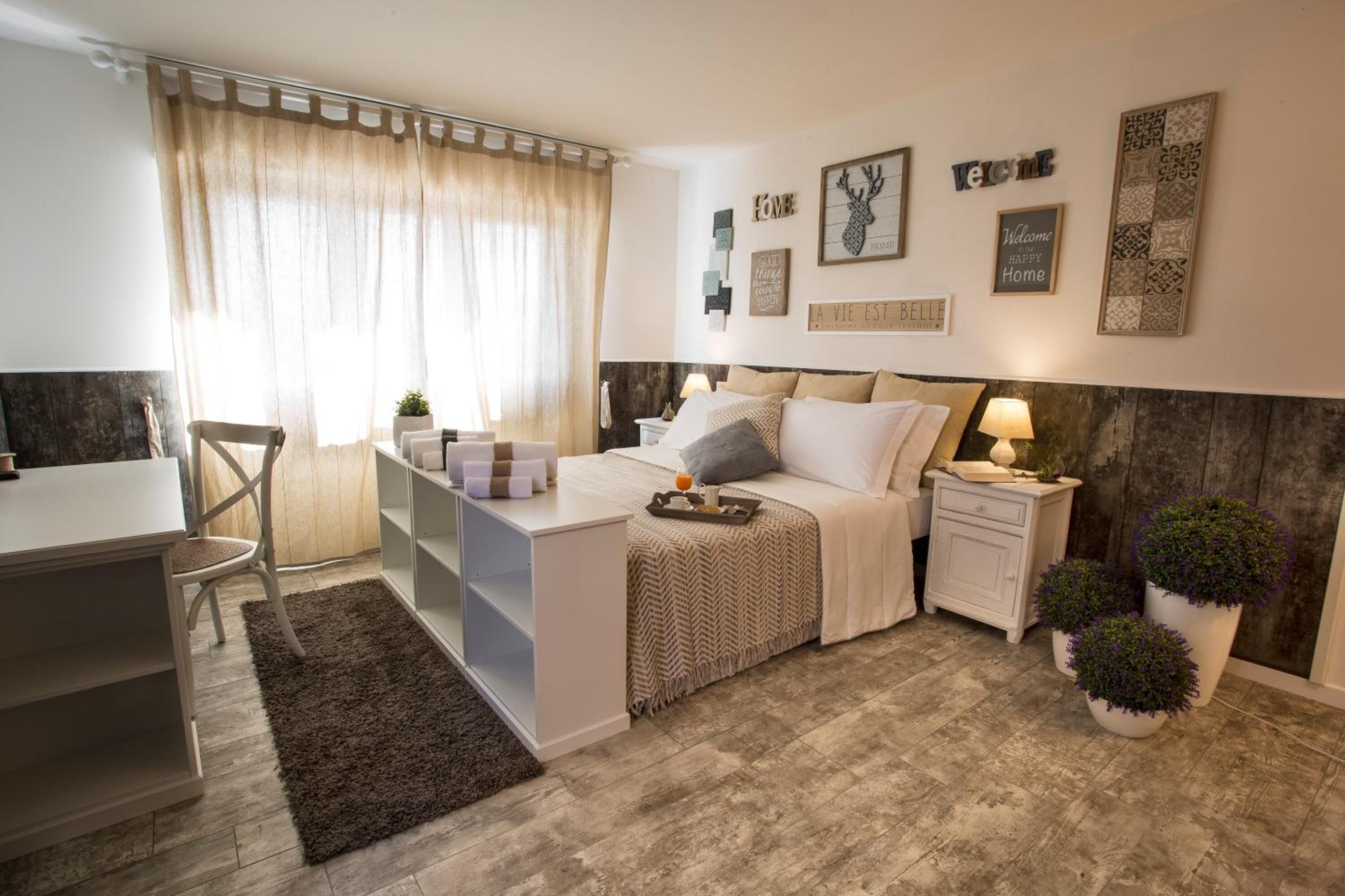 A cozy bedroom with a bed, bedside tables, a desk, and a chair.