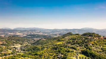 Una vista panorámica de un paisaje montañoso con edificios dispersos, probablemente una zona rural o semi-rural.