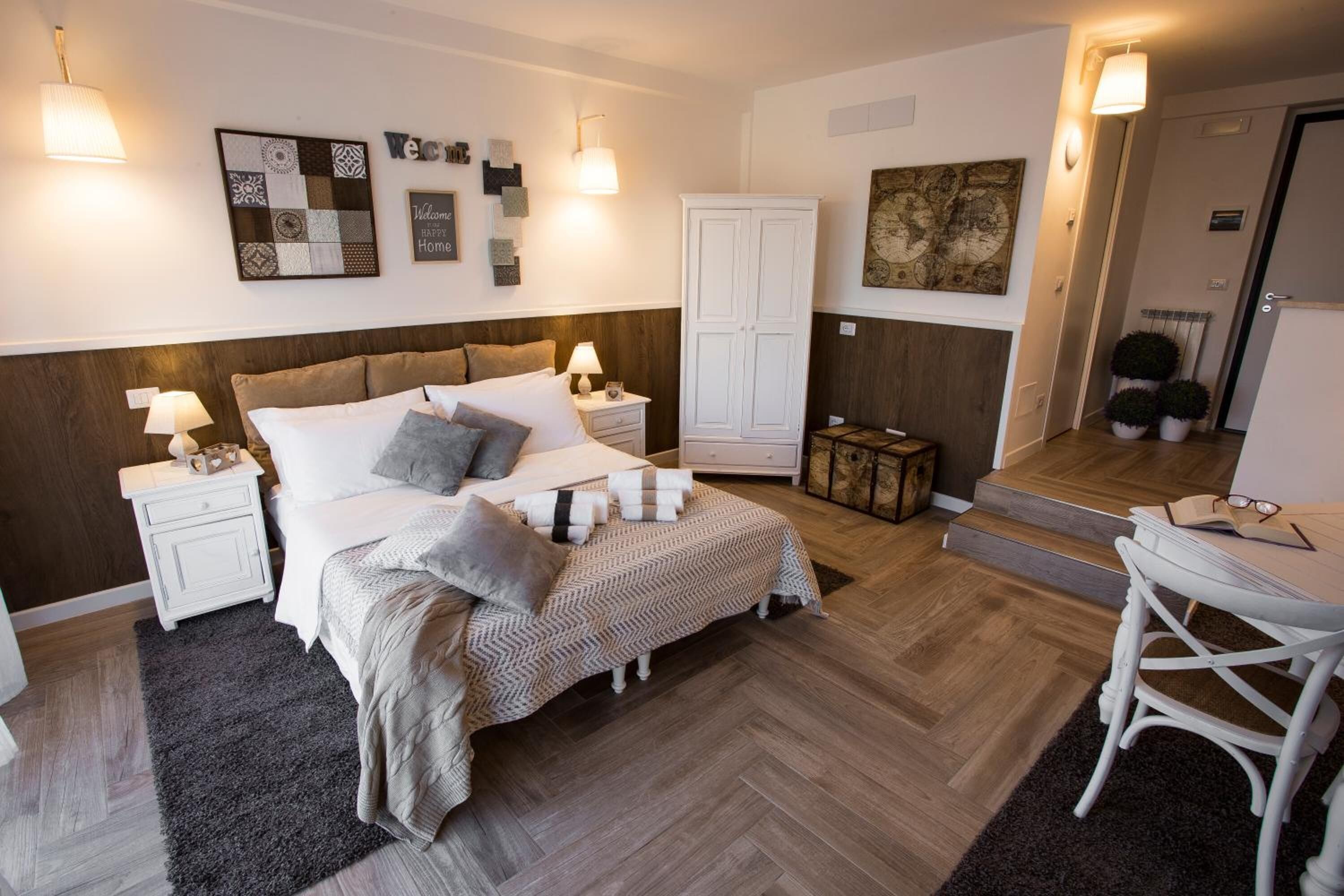A bedroom with a bed, nightstands, a wardrobe, a desk with a chair, and a mirror.