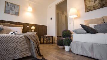 Un dormitorio con cama, mesitas de noche, cómoda, sofá y dos plantas en macetas.
