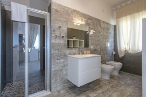 Deluxe driepersoonskamer | Badkamer | Een douche, gratis toiletartikelen, een haardroger, badjassen