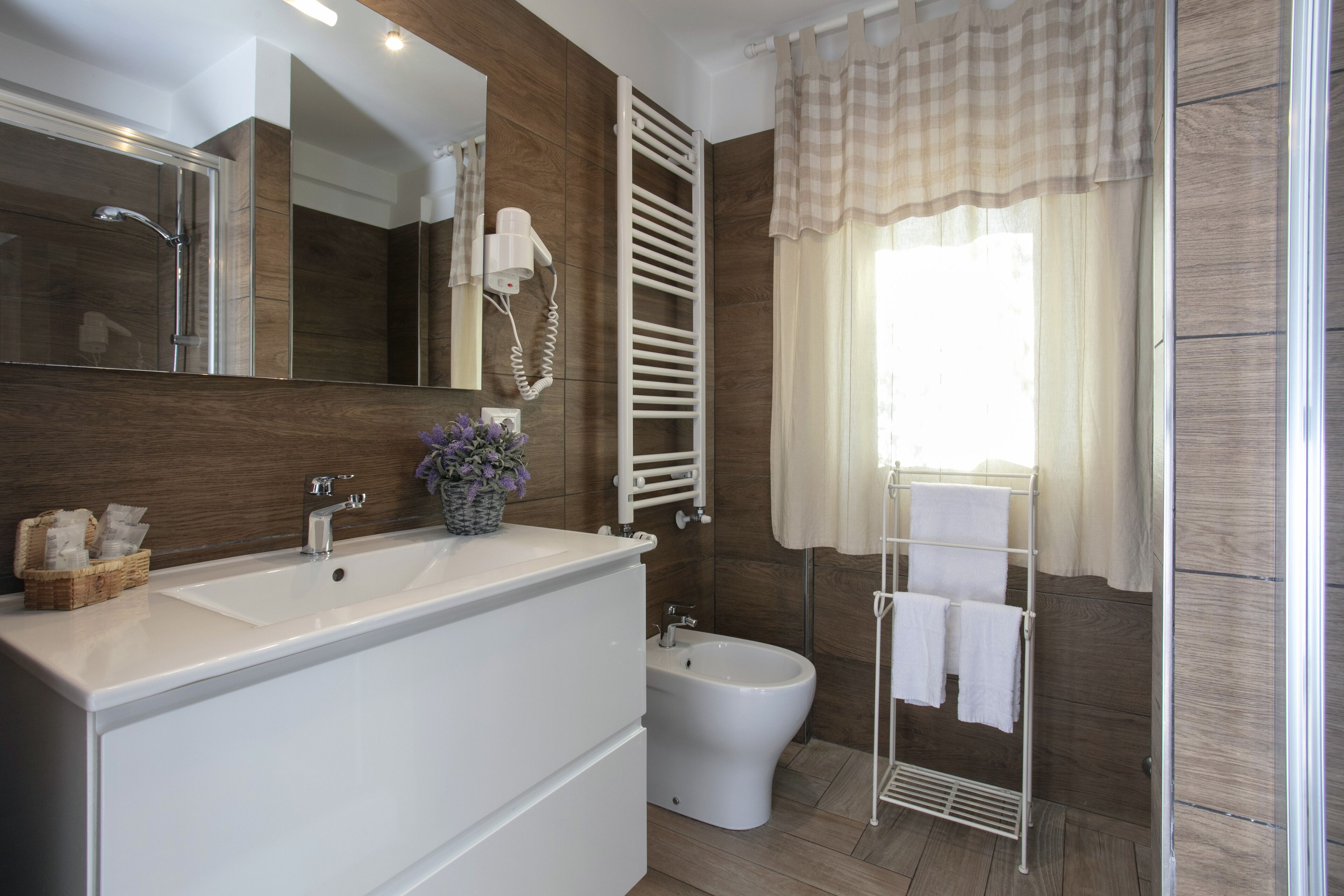 A modern bathroom with a large sink, a bidet, a towel rack, and a mirror.