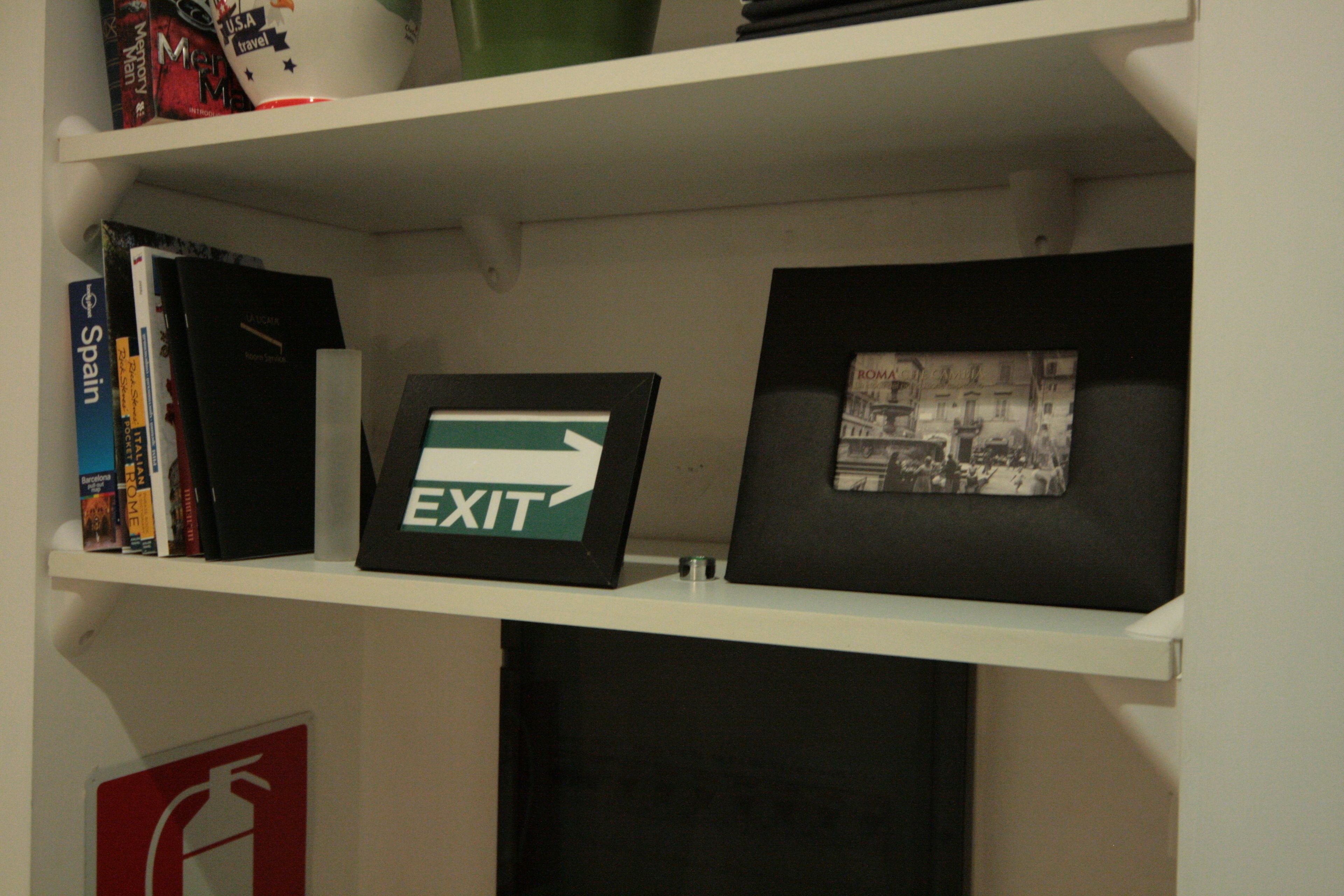 A shelf with books, a framed EXIT sign, and a framed photograph.
