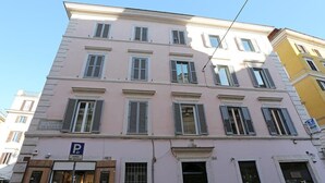 Un immeuble à plusieurs étages, avec un commerce au rez-de-chaussée et un panneau indiquant un parking.