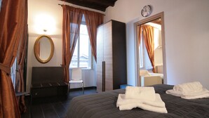 Une chambre d’hôtel avec un lit, une chaise, une armoire, un miroir et une horloge au mur.