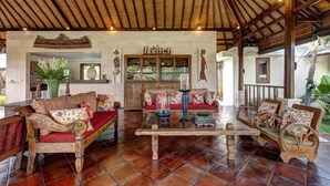 Un amplio salón con mobiliario de madera, suelo de baldosas y un alto techo con vigas a la vista.