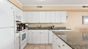 A kitchen with white cabinets, a granite countertop, and a built-in oven.