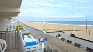 A beachside promenade with benches, a sign for telescope sessions, and a view of the ocean.