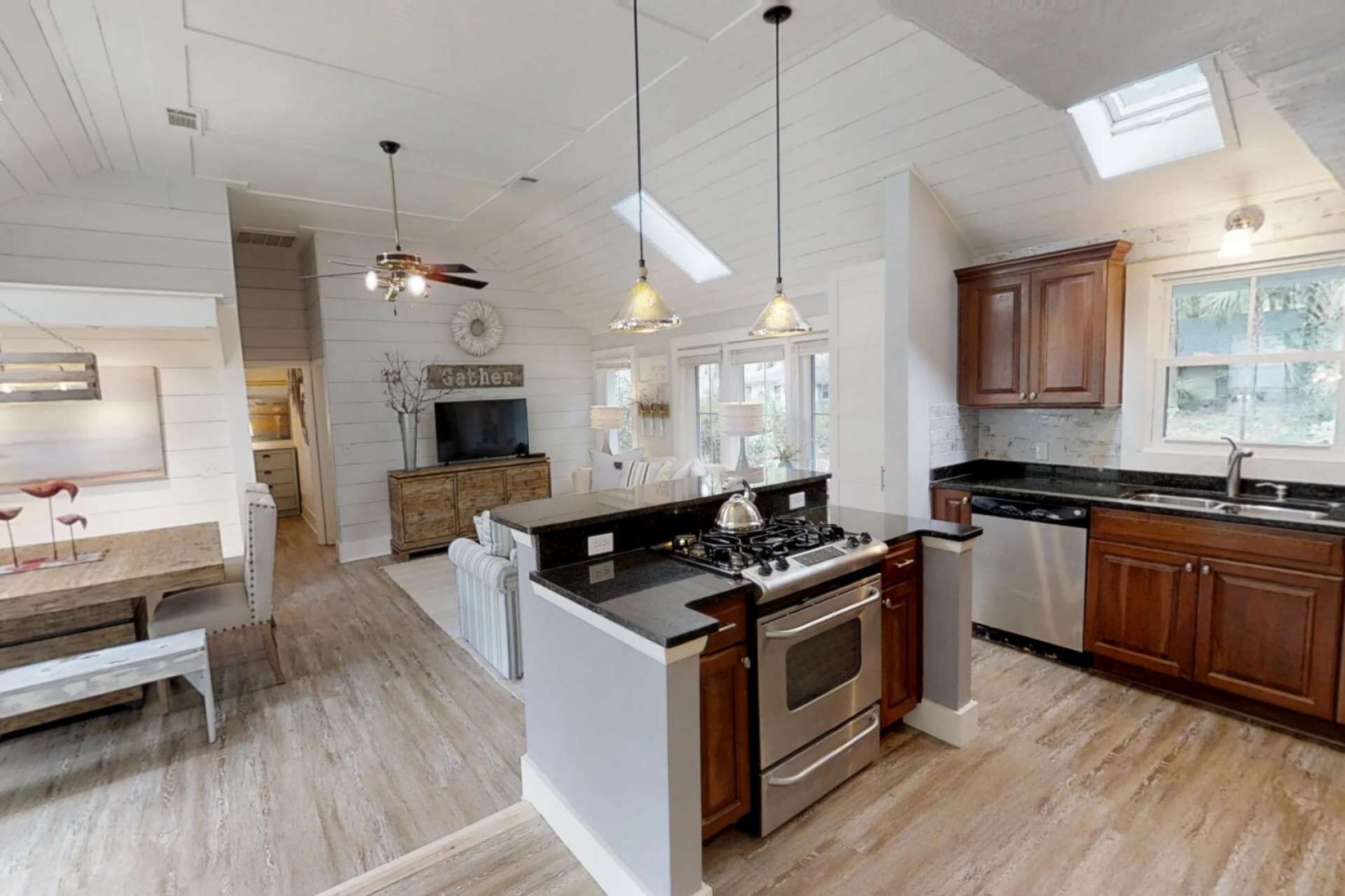 A spacious kitchen with wooden cabinets, a central island with a stove, and pendant lighting.