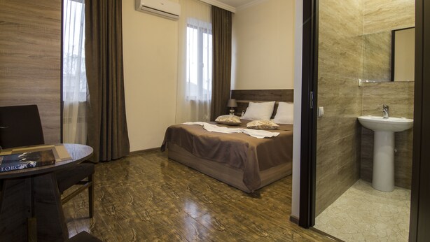 Una habitación de hotel con cama, mesita de noche y baño con lavamanos.