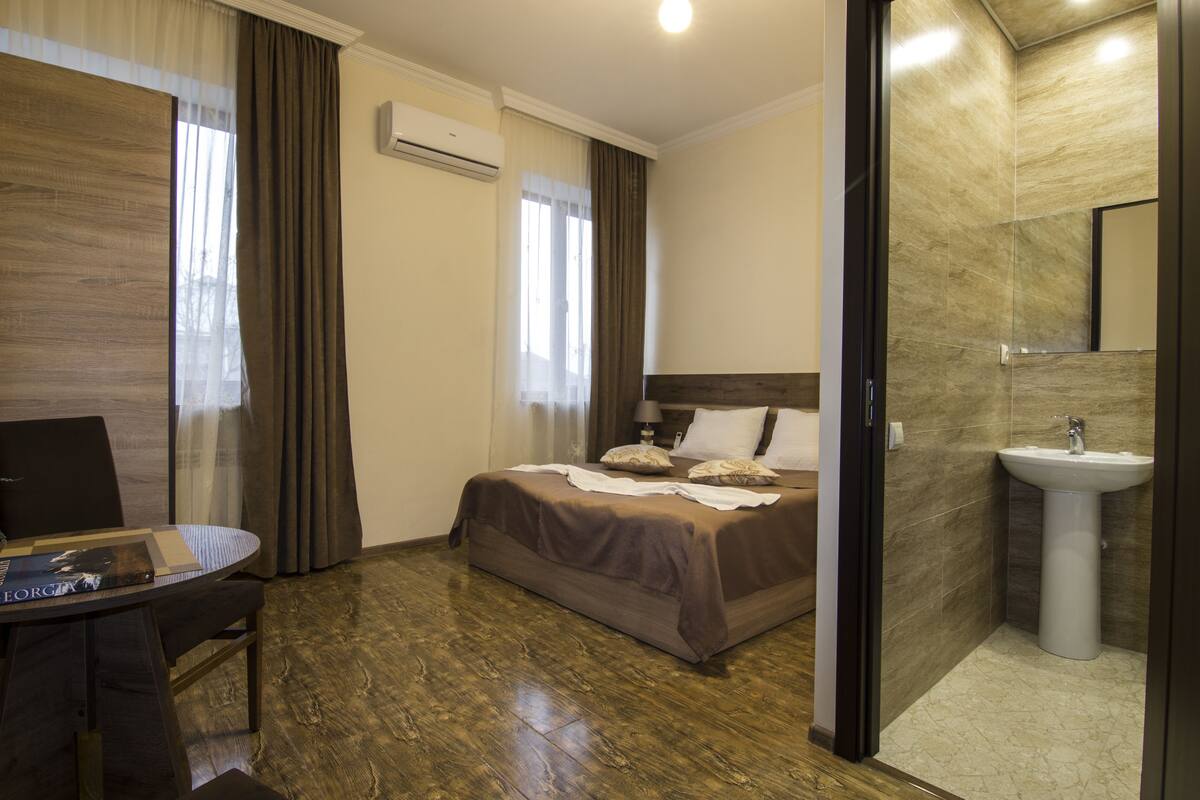 A hotel room with a bed, bedside table, and a bathroom with a sink.
