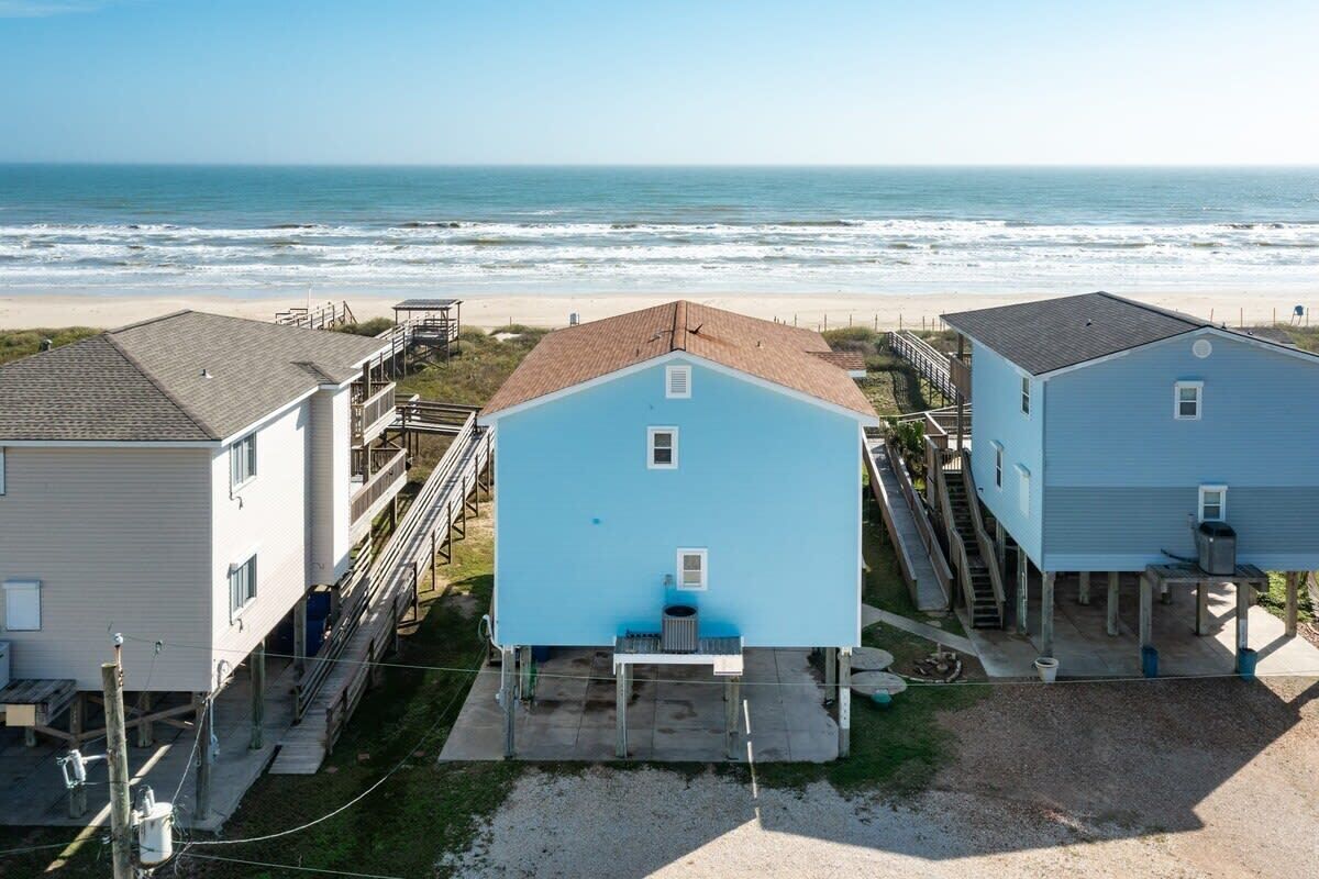 A beachfront property with three houses, each with a distinct roof color.