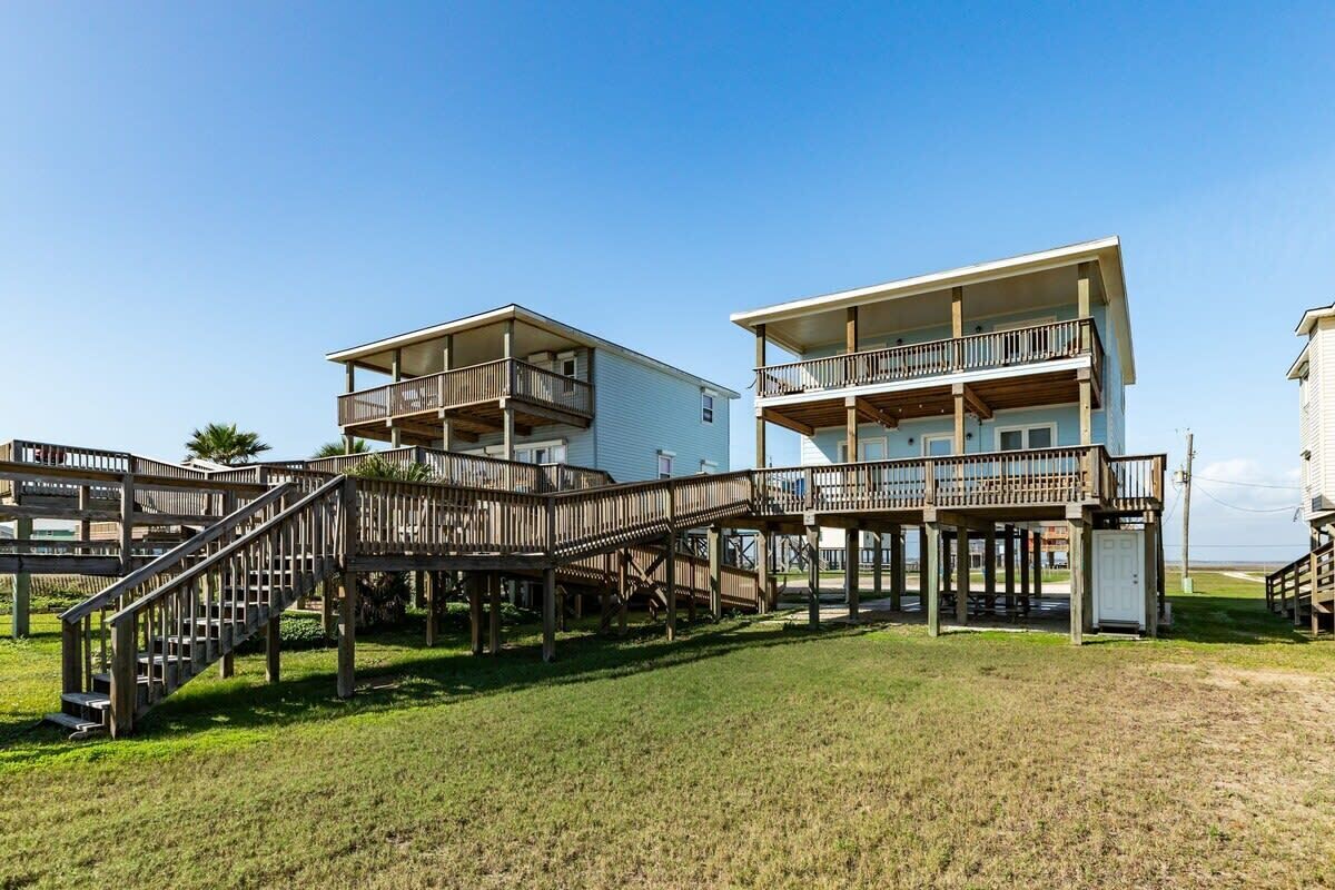 A beachfront property with a wooden deck connecting two buildings, each with balconies.