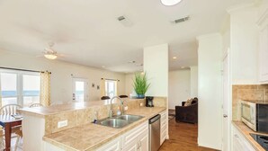 Uma cozinha moderna com uma ilha central, eletrodomésticos de aço inoxidável e vista para a sala de estar.