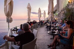 A seaside restaurant with outdoor seating, overlooking the ocean.