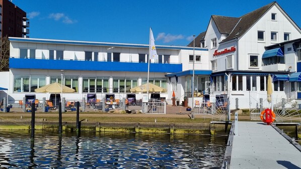 Un hotel frente al agua con terraza exterior y un muelle.
