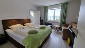 Een hotelkamer met een groot bed, een kleine tafel, een zithoek en uitzicht op de omgeving.
