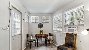 A dining area with a round table, four chairs, and a decorative wall piece. - 1 bedroom Apartment in quaint triplex 12 blocks from UF and downtown (Gainesville)
