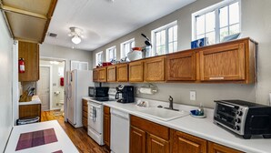 A kitchen with wooden cabinets, a white countertop, a sink, a stove, and a toaster. - 1 bedroom Apartment in quaint triplex 12 blocks from UF and downtown (Gainesville)