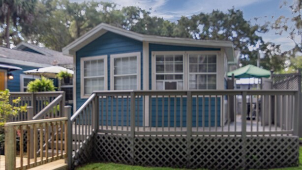 A small, single-story house with a deck, a fenced yard, and a green umbrella. - 1 bedroom Apartment in quaint triplex 12 blocks from UF and downtown (Gainesville)