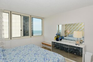 A bedroom with a bed, a dresser, a mirror, and a view of the sea. - XPLORIE ACTIVITIES & LINENS INCLUDED*! QUAY 2 BR/2 BA Ocean View Condo with Indoor/Outdoor Pools. (Ocean City)