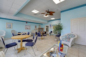 A room with a ceiling fan, multiple tables and chairs, a potted plant, and a door. - XPLORIE ACTIVITIES & LINENS INCLUDED*! QUAY 2 BR/2 BA Ocean View Condo with Indoor/Outdoor Pools. (Ocean City)
