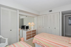 A bedroom with two beds, a dresser, a mirror, and a wardrobe with louvered doors.