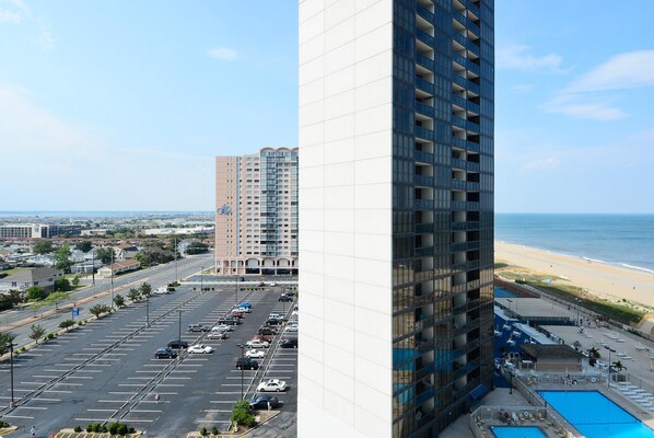 A high-rise building with a parking lot and a beach view. - XPLORIE ACTIVITIES & LINENS INCLUDED*! QUAY 2 BR/2 BA Ocean View Condo with Indoor/Outdoor Pools. (Ocean City)
