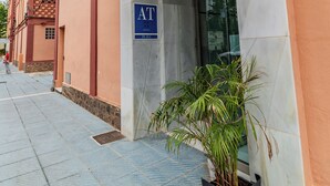 A building entrance with a sign reading "AT" and a potted plant. - Las Yucas  (Velez-Malaga)