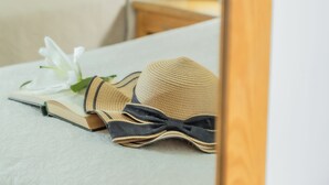 A neatly made bed with a white pillow, a book, and a straw hat. - Las Yucas  (Velez-Malaga)