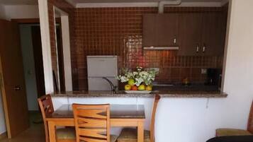Un espacio habitable compacto con comedor, kitchenette y sofá.