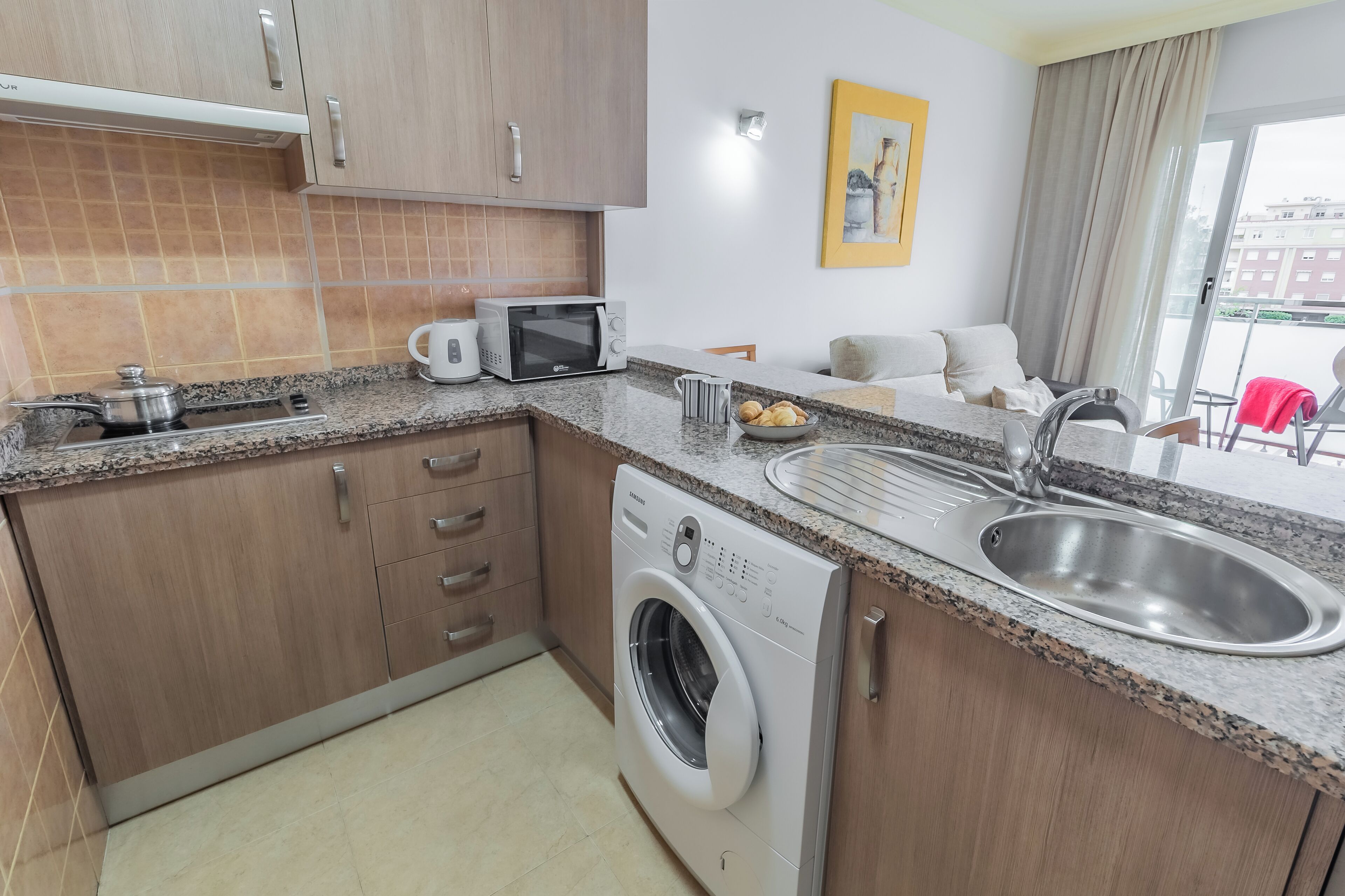 A compact kitchen with a built-in washing machine, a microwave, and a sink.