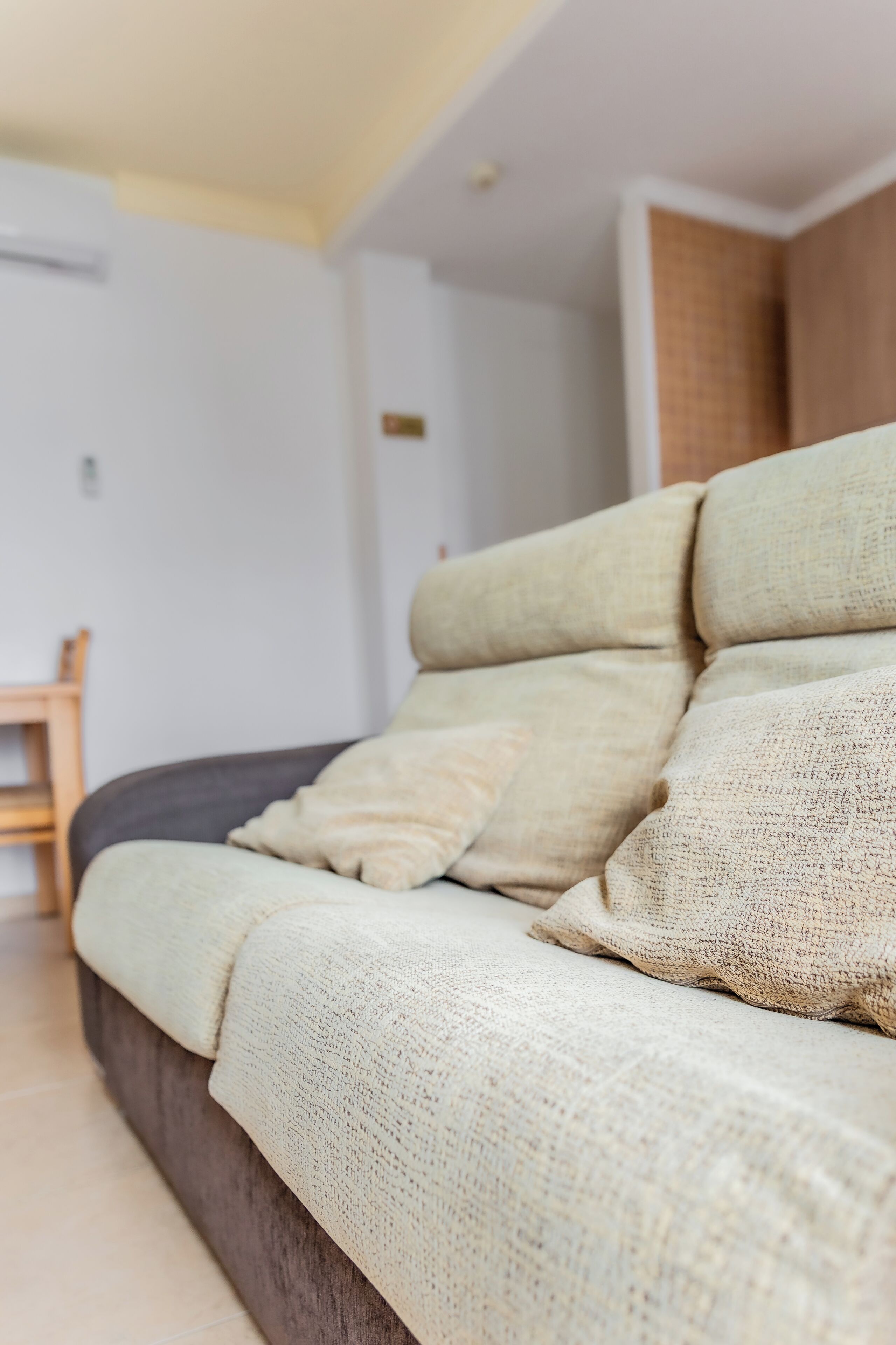 Un salon moderne avec un canapé, un fauteuil en bois et un sol carrelé.