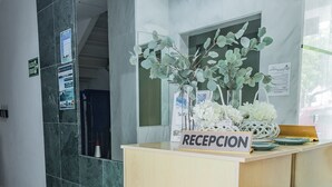 A reception desk with a sign reading "RECEPCION," a mirror, and a potted plant. - Las Yucas  (Velez-Malaga)