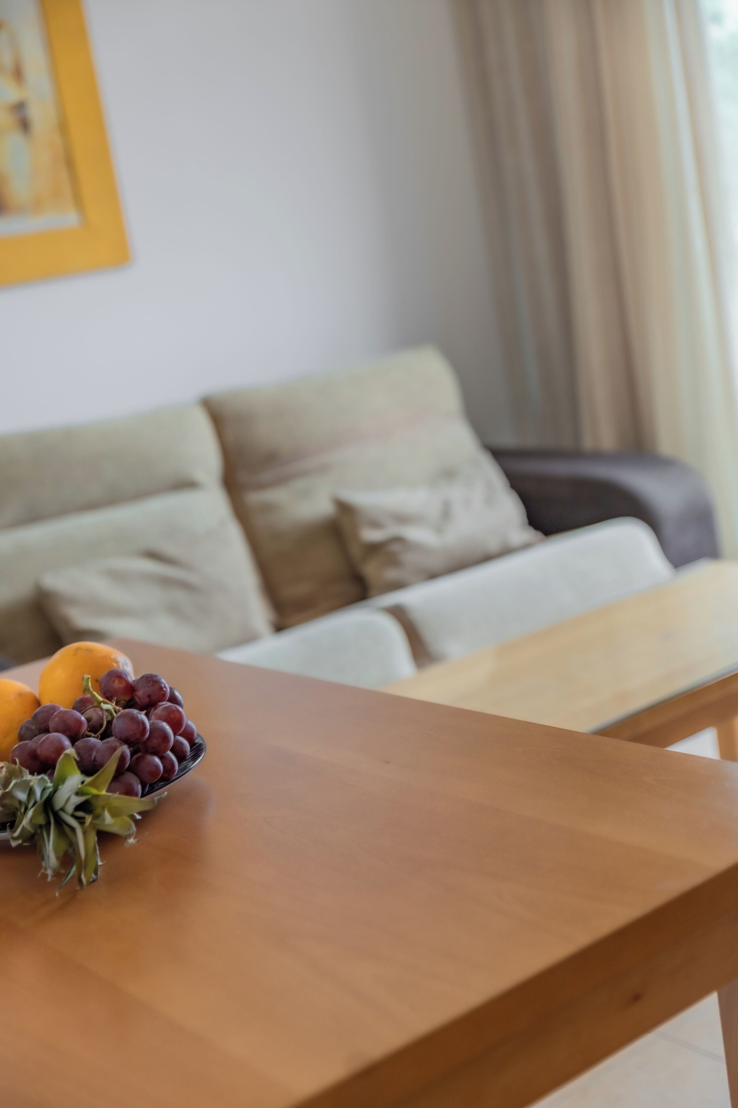 Una mesa de madera con un bol de uvas y una naranja.