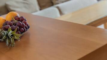 Una mesa de madera con un bol de uvas y una naranja.