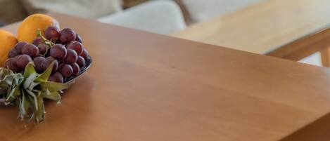 Una mesa de madera con un bol de uvas y una naranja.