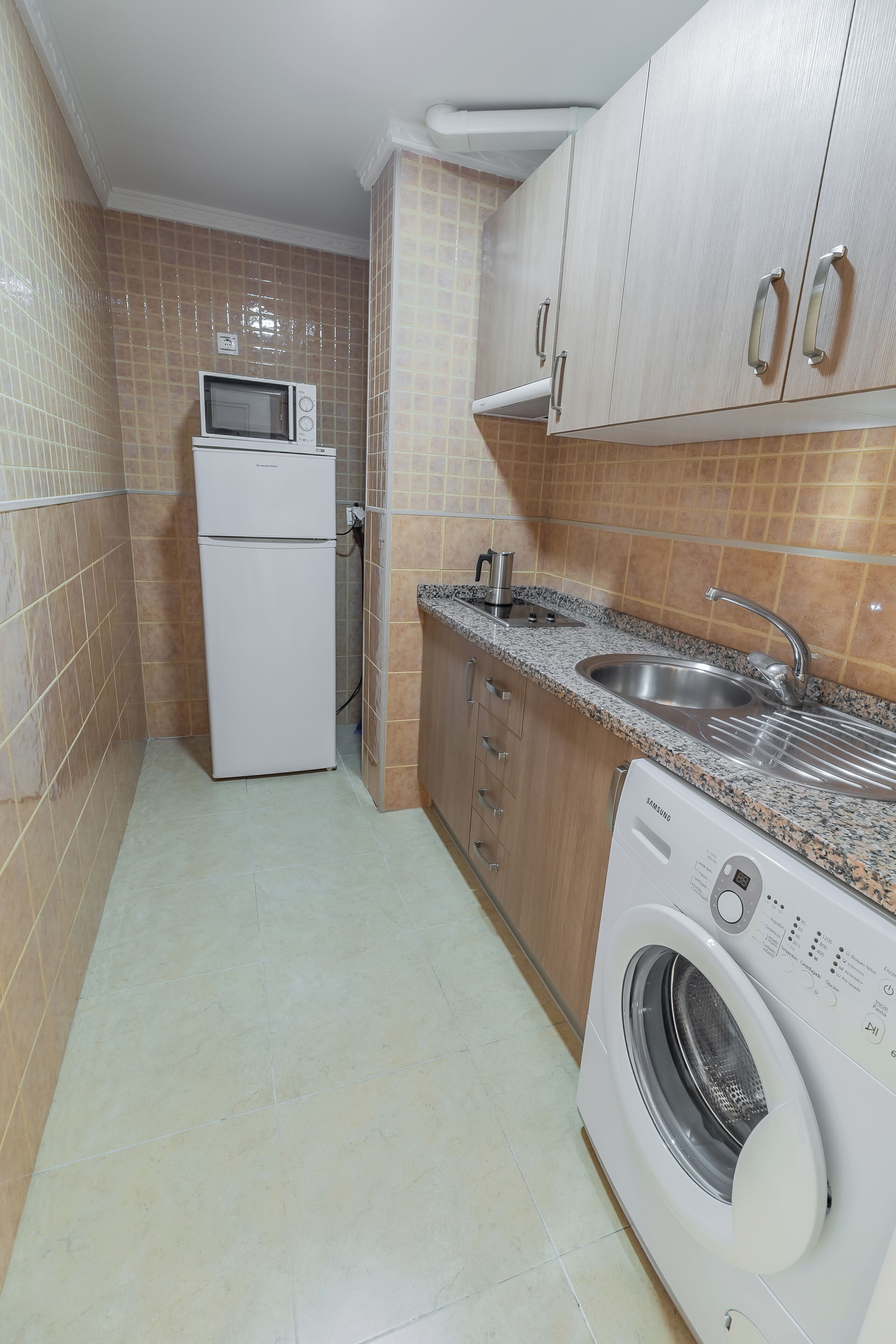 Cocina compacta con microondas, lavamanos y lavadora.
