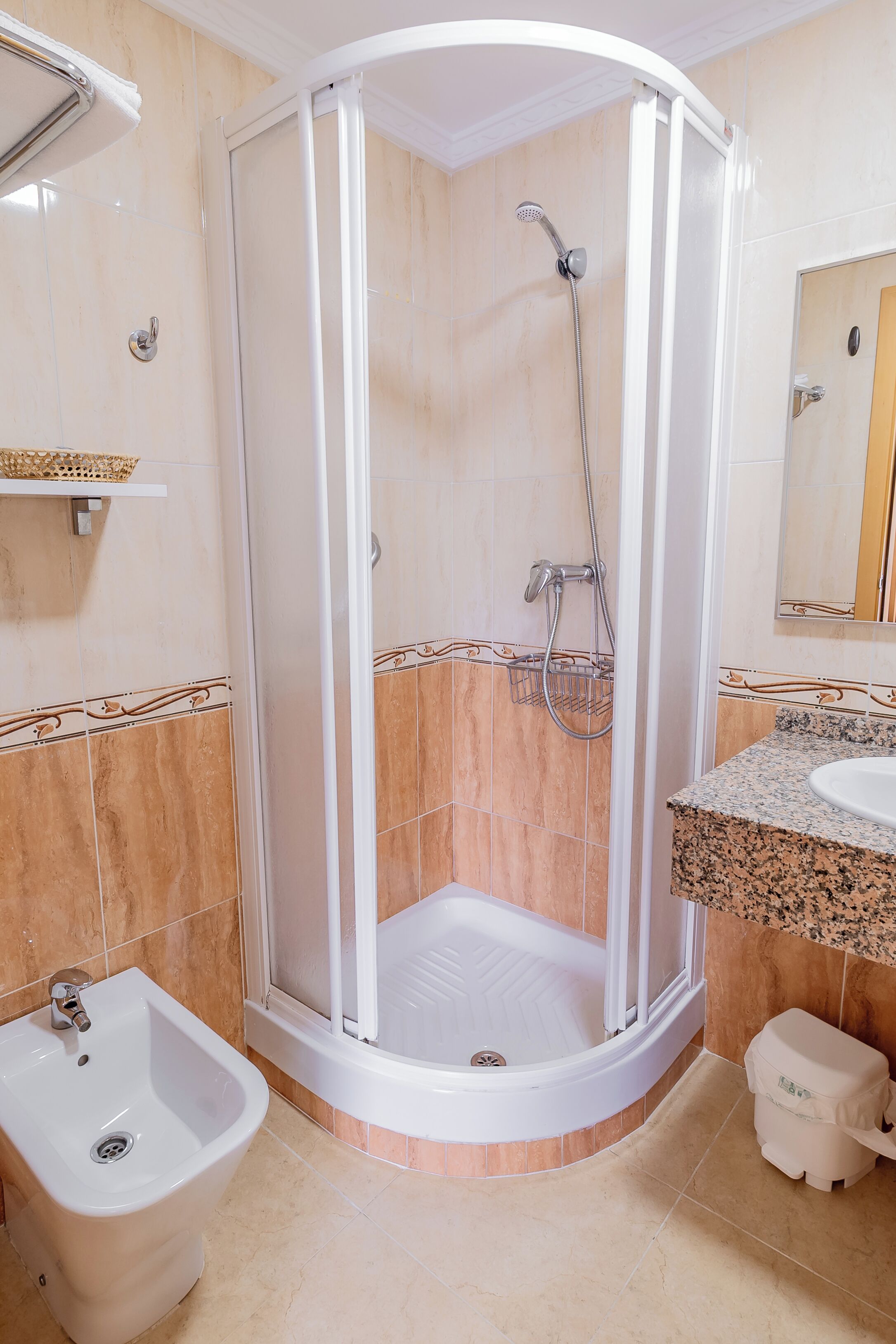 Un baño con cabina de ducha, un bidé, un lavabo y un espejo.