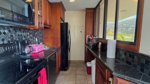A kitchen with wooden cabinets, a black stove, and a refrigerator. - Our Home is Your Home in St Thomas, ~USVI~ (Charlotte Amalie)