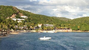 A coastal resort with beachfront villas, a boat in the water, and palm trees. - Our Home is Your Home in St Thomas, ~USVI~ (Charlotte Amalie)