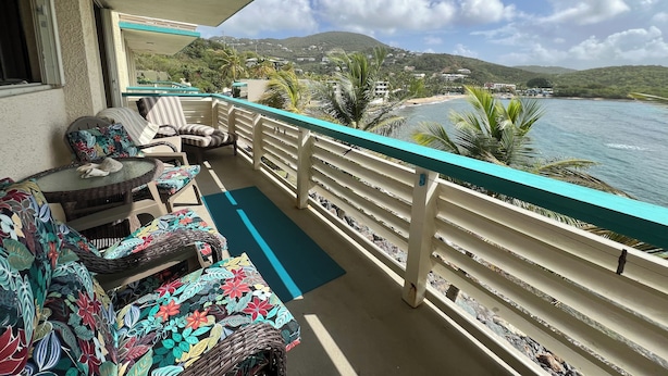 A balcony with wicker furniture and a view of the sea and hills. - Our Home is Your Home in St Thomas, ~USVI~ (Charlotte Amalie)