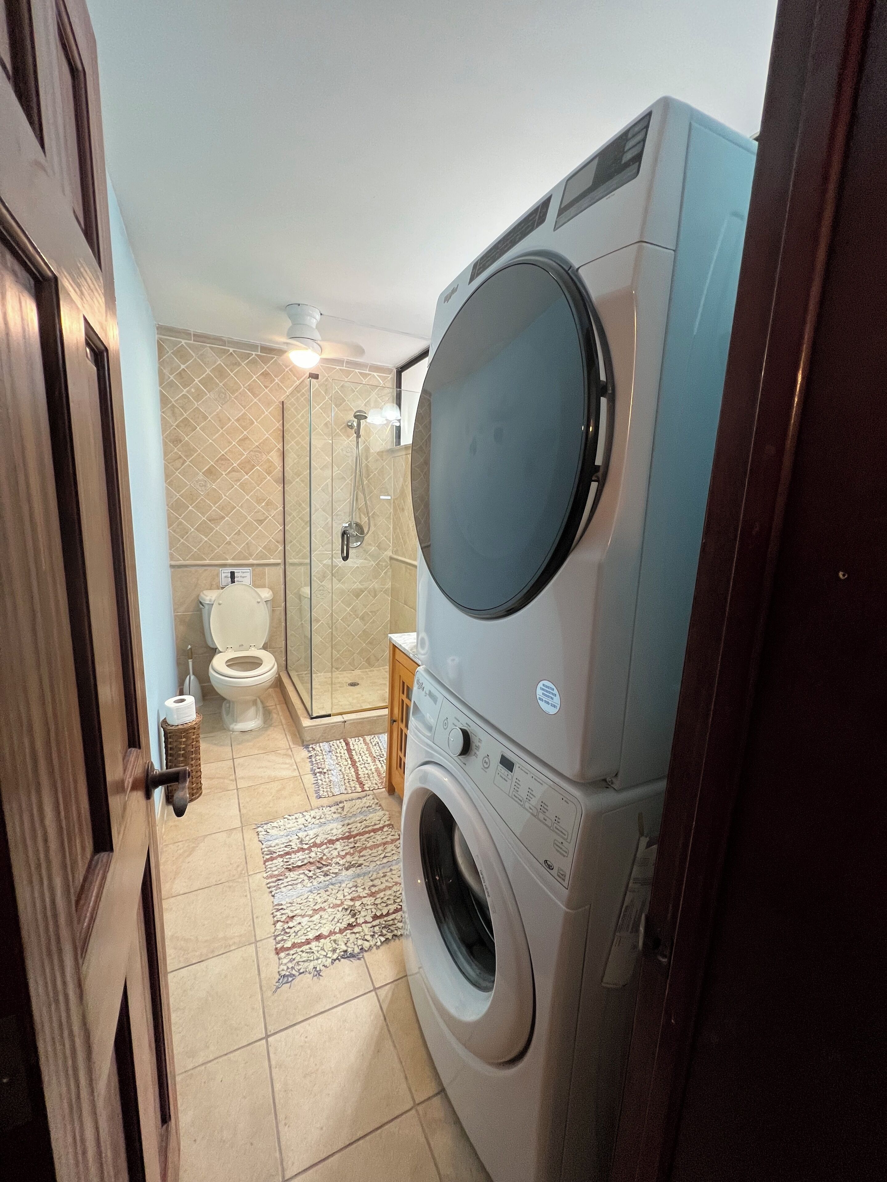 Un baño pequeño con lavadora, inodoro y cabina de ducha de vidrio.