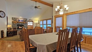 A dining area with a fireplace, wooden furniture, and a view of the outside.