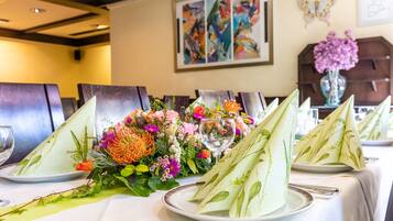 Una mesa de comedor servida con platos, servilletas y un centro de mesa floral.