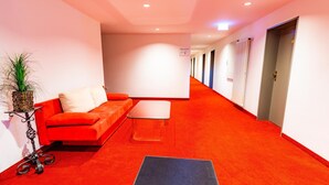 A hotel lobby with a red carpet, a sofa, a small table, and a potted plant. - Gasthof Pension Post (Denkendorf)