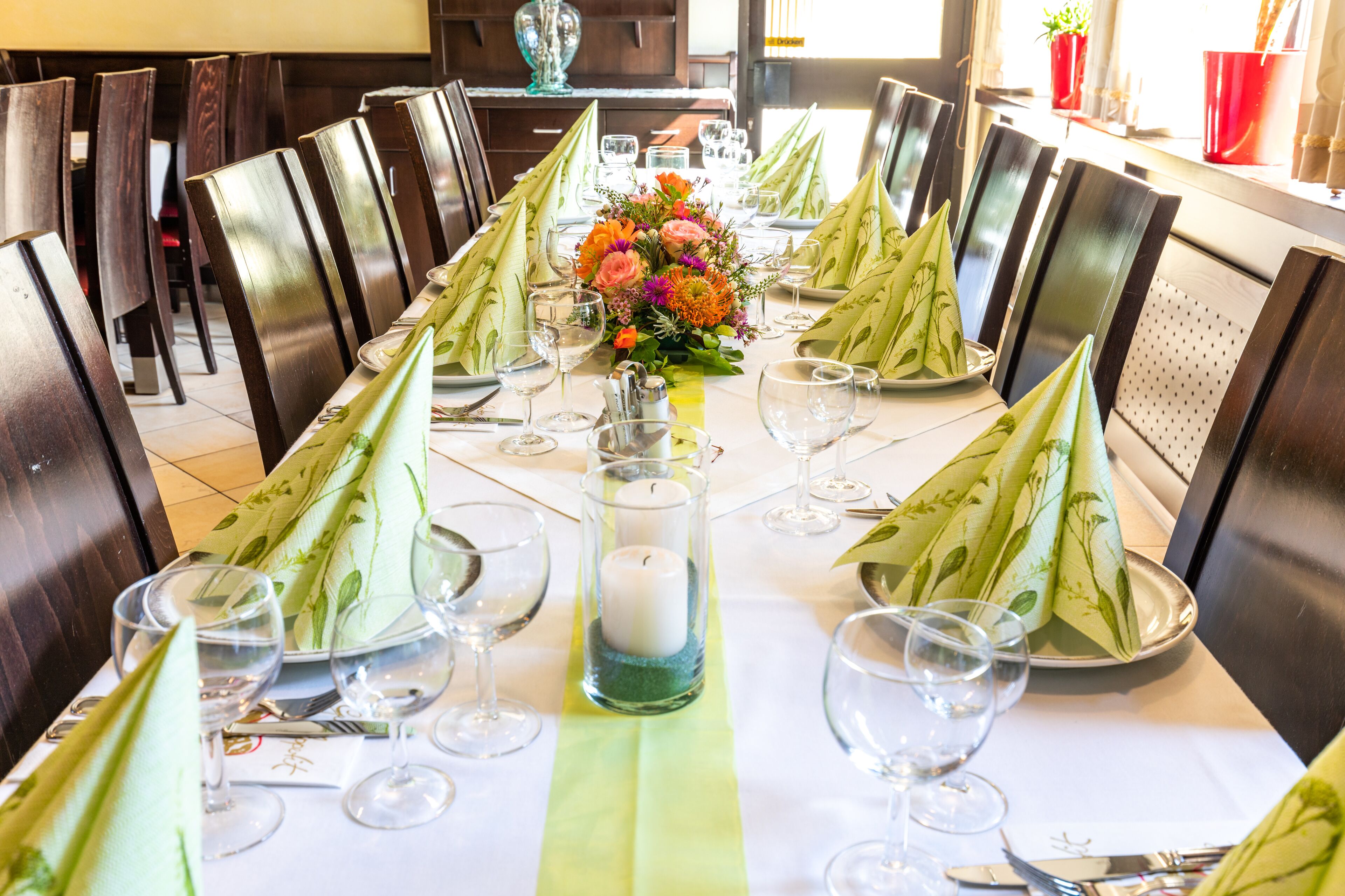 Mesa de comedor lista para una comida, con sillas, un centro de mesa y cristalería.